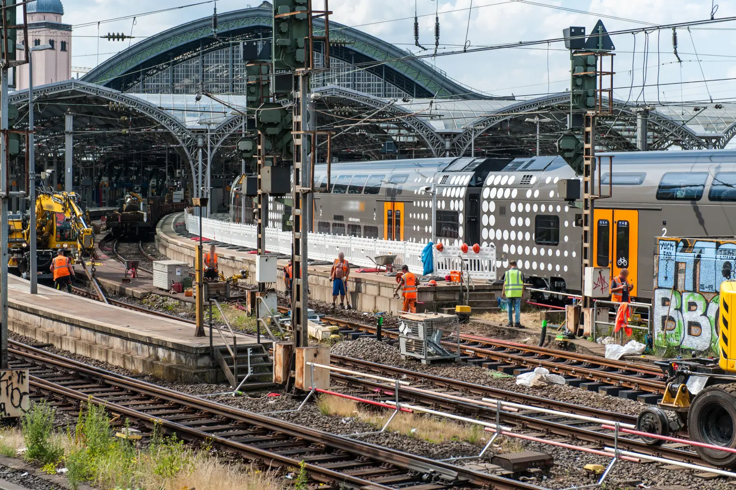 Ein Regionalzug fährt in den Bahnhof in Köln ein, während Arbeiter neue Gleise bauen
